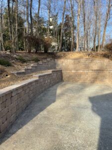 A large stone two-tiered retaining wall at the edge of a driveway