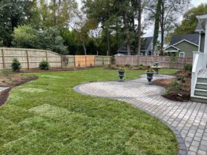 Two stone circular patio areas connected by walkways. Fresh sod, new mulch, and appropriate plants complete the landscape design.