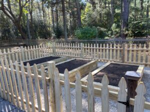 Wodden raised bed garden area with a picket fence surrounding it to keep animals out.
