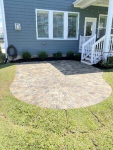 stone patio at the bottome of a small stair case with a circle accent and fresh sod in the yard.